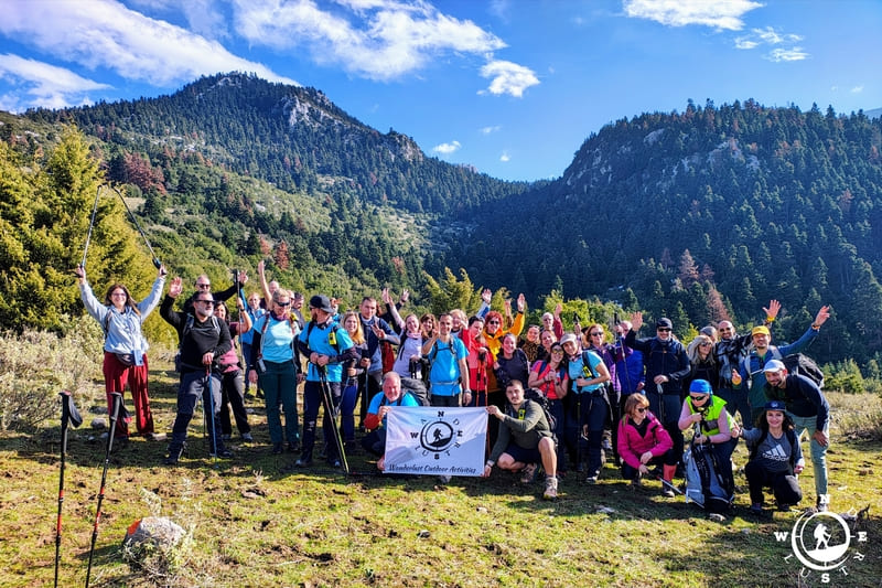 Η ομάδα της Wanderlust σε ορεινό ξέφωτο, με φόντο τις ελατοσκέπαστες πλαγιές του Παρνασσού.