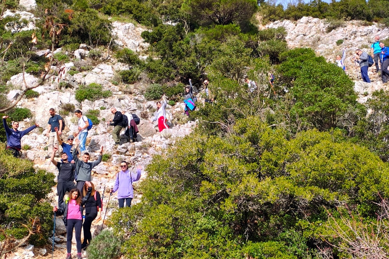 The Wanderlust group hiking through Megali Houni gorge on Mount Parnitha surrounded by rocky terrain and green slopes
