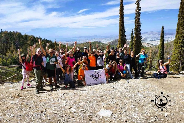 Wanderlust hiking group on Mount Hymettus holding the team flag